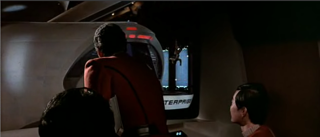 從 Kirk 等人的交通梭看出去，是 Enterprise 艦尾的交通梭港口，有一個工作人員正往下移動