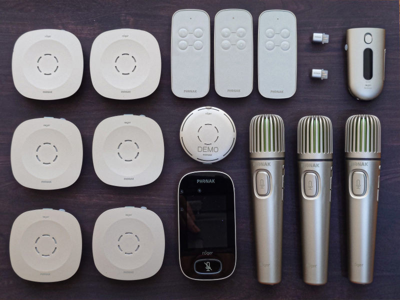 6 台 Roger Table Mic、3 支 Roger Table Mic 遙控器、1 台 Roger Select、1 支 Roger Touchscreen Mic、2 顆 Roger X、1 台 Roger NeckLoop、3 支 Roger Pass-around 平放排列整齊